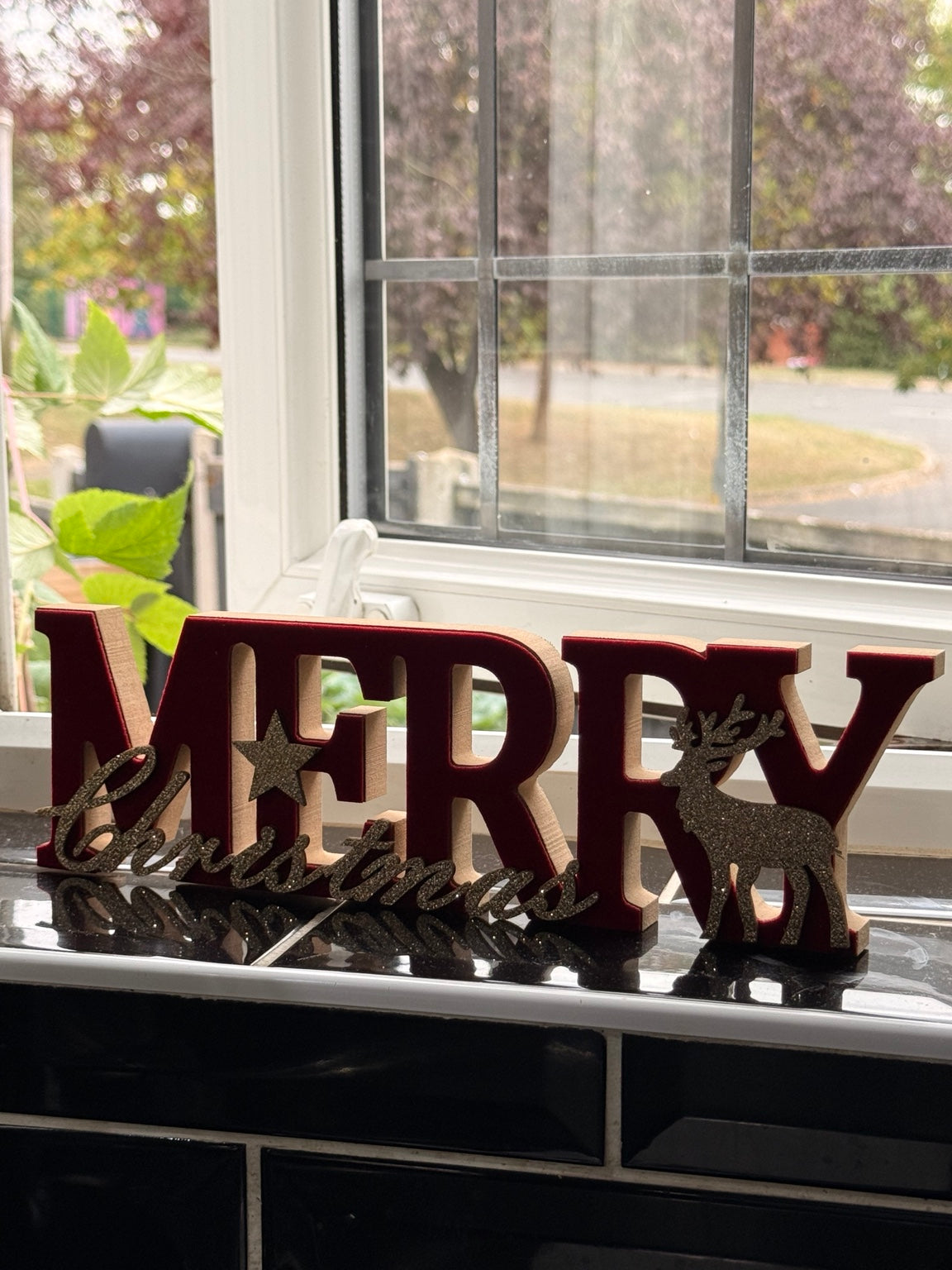 Merry Christmas wooden decoration displayed on windowsill